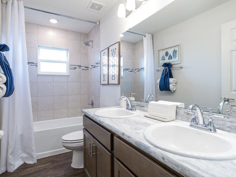 A dual vanity hall bath serves the secondary bedrooms and guests - Serendipity model home in Auburndale, FL