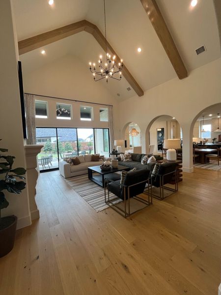 An elegant living room with vaulted ceilings, a modern chandelier, and large windows overlooking a scenic view.