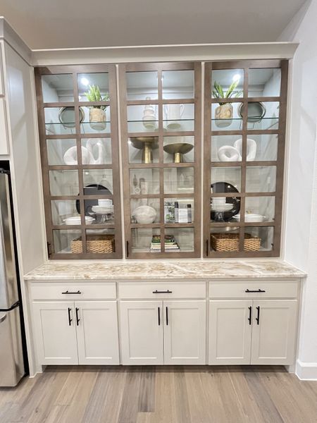 Elegant built-in cabinetry with glass doors, decorative items, and marble countertop enhancing the kitchen’s charm.