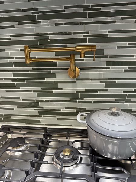 Modern kitchen with a sleek gas stove, stylish pot filler, and elegant backsplash tiles.