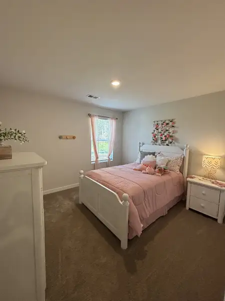 A cozy bedroom with a white bed, pink bedding, soft lighting, and a charming nightstand. A cozy bedroom with a white bed, pink bedding, soft lighting, and a charming nightstand.