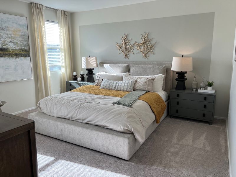 A cozy bedroom with a plush grey bed, stylish nightstands, modern lamps, and elegant wall art.