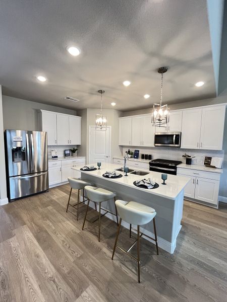 A modern kitchen with white cabinets, a sleek island, and stylish pendant lighting.