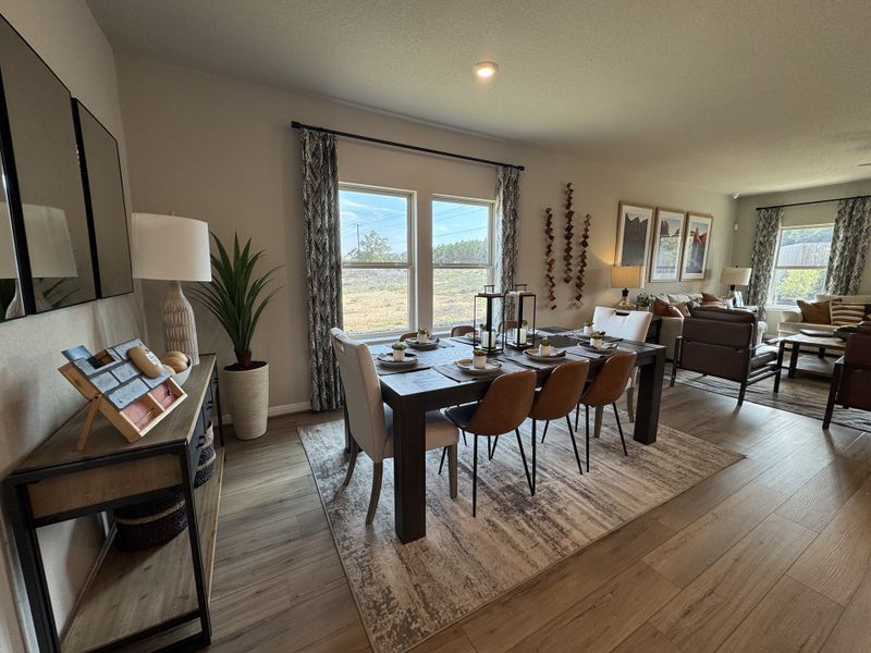 A chic dining room with a modern table, elegant decor, and large windows offering a scenic view.