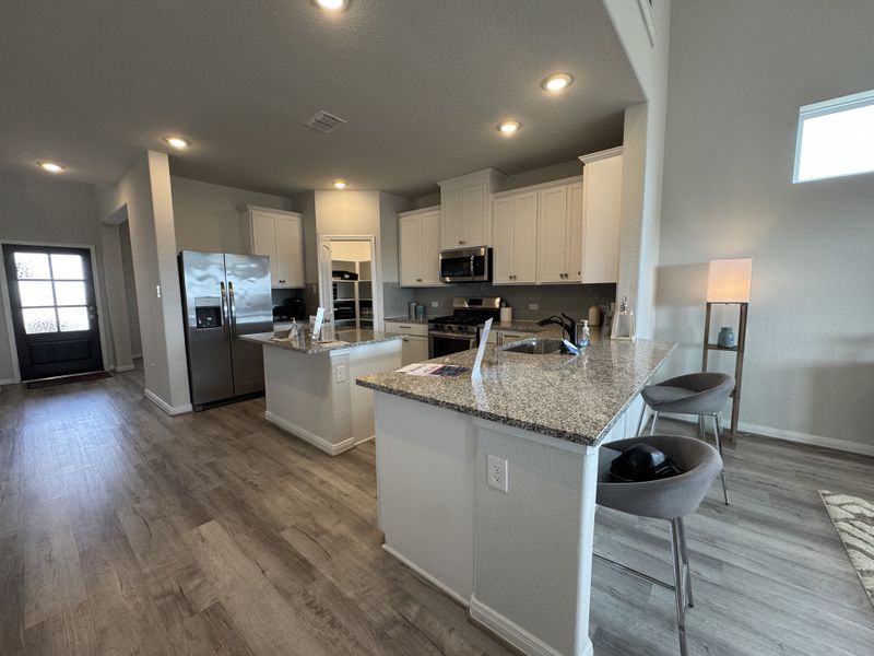 A modern kitchen with granite countertops, sleek stainless steel appliances, and elegant wood flooring.