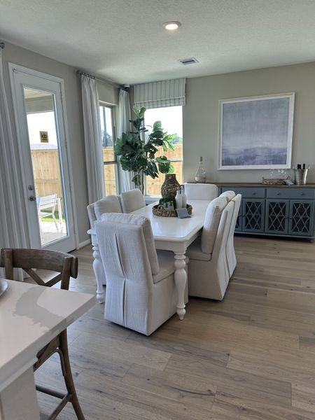 A cozy dining area with soft upholstered chairs, a white table, and a large window for natural light.