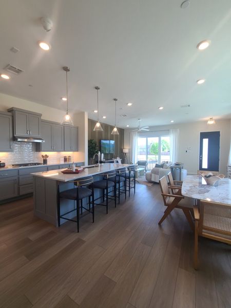 A spacious open-concept kitchen and living area with modern fixtures, large island, and elegant dining space.