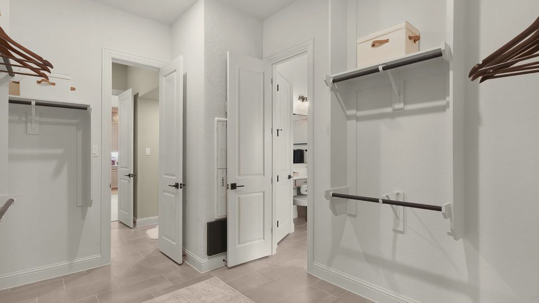 Spacious owner’s closet with wooden hanging rods and direct access to the laundry room for convenience.