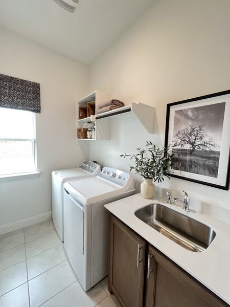 A sleek laundry room featuring modern appliances, ample storage, and a stylish countertop with a stainless steel sink.