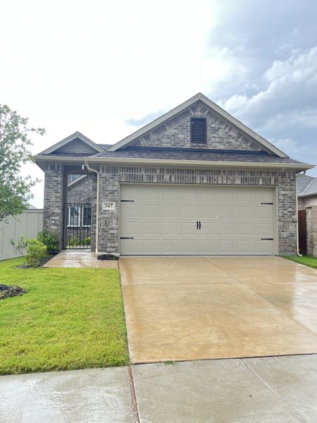 A charming gray brick home with a spacious driveway in Elevon by Pacesetter Homes (Lavon, TX).