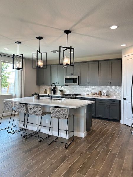 A modern kitchen with sleek gray cabinets, a spacious island, and contemporary pendant lighting.