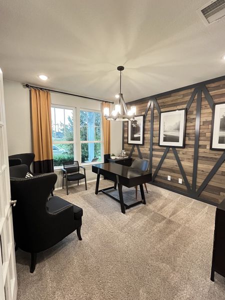 A sophisticated office with a wooden accent wall, elegant black furniture, and warm lighting creates a cozy, productive space.