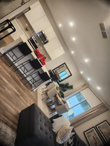 A modern open-concept kitchen and living area with sleek cabinetry, warm flooring, and cozy seating.