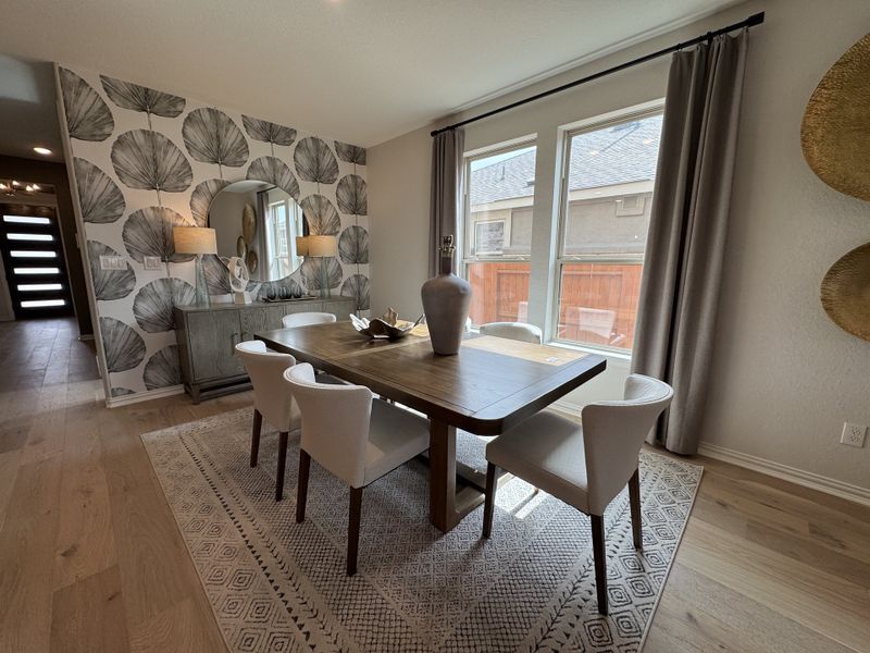 A modern dining room featuring a wooden table, elegant chairs, patterned wallpaper, and ample natural light. A modern dining room featuring a wooden table, elegant chairs, patterned wallpaper, and ample natural light.