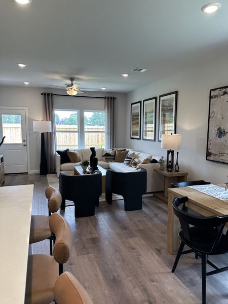 An inviting living space with modern decor, cozy seating, and large windows. Beige and black tones accentuate the room.