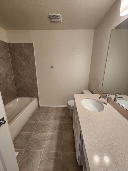 A contemporary bathroom featuring a sleek vanity, tiled floor, and a modern bathtub with neutral tones.