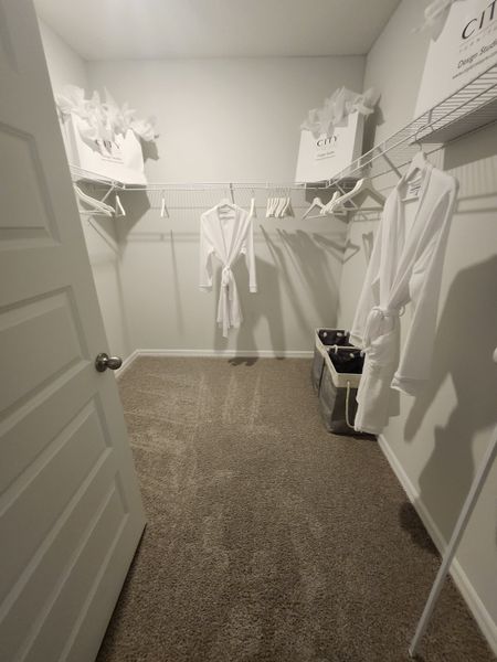 A spacious walk-in closet with ample shelving, soft carpet, and elegant robes for a luxurious touch.
