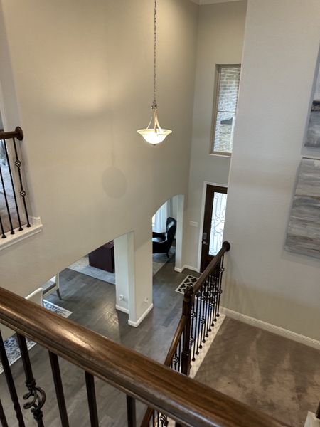 A spacious foyer with elegant railings, high ceilings, and a warm light fixture, offering a welcoming interior view. A spacious foyer with elegant railings, high ceilings, and a warm light fixture, offering a welcoming interior view.