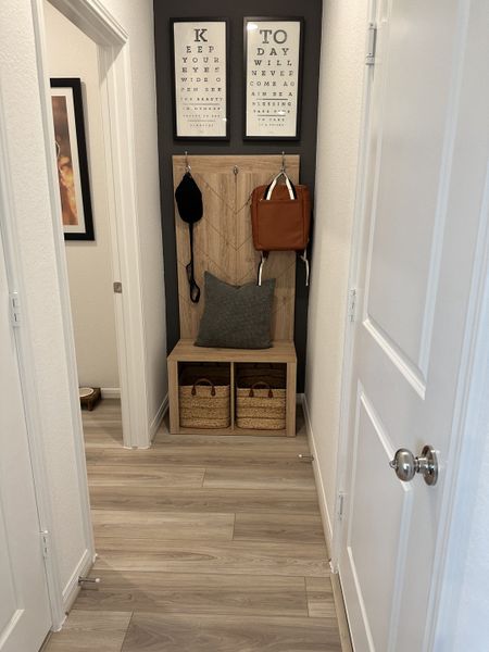 A cozy entryway nook with decorative wall art, hanging hooks, and storage baskets on light wood flooring. A cozy entryway nook with decorative wall art, hanging hooks, and storage baskets on light wood flooring.