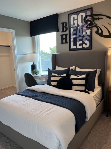 A stylish bedroom with a gray upholstered bed, sports-themed decor, and a cozy ambiance.