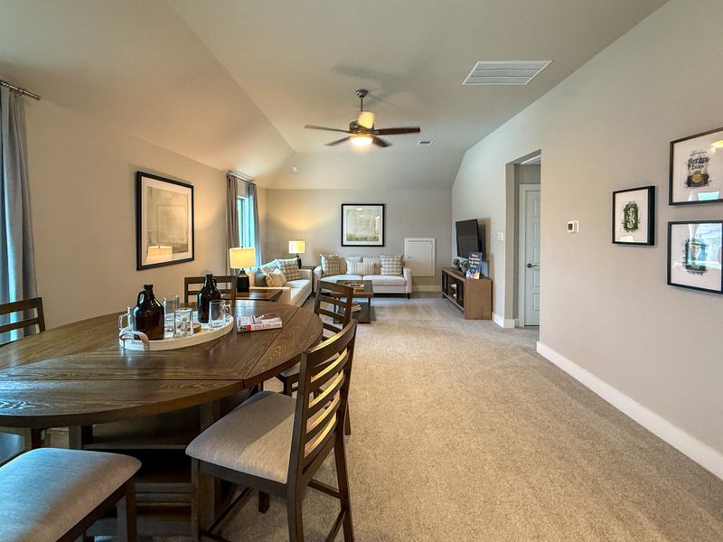 A cozy living and dining area with a sleek table, ceiling fan, and inviting seating accents.