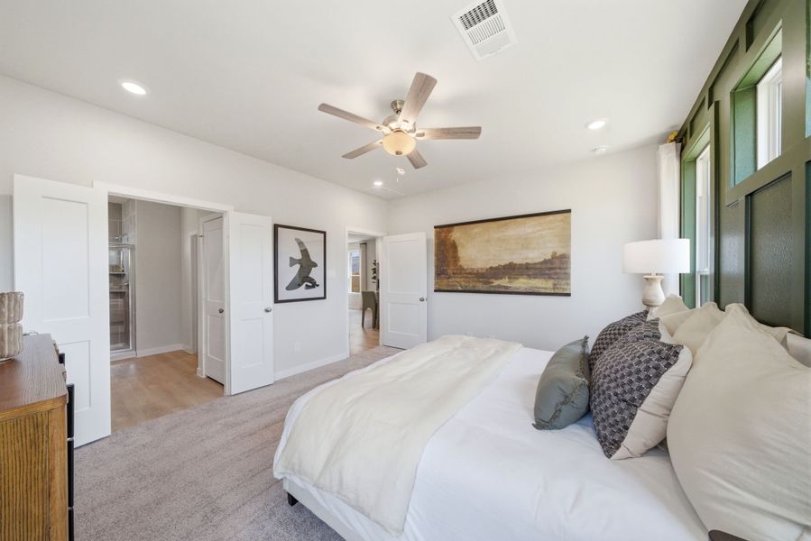 A bedroom with a ceiling fan and a bed.