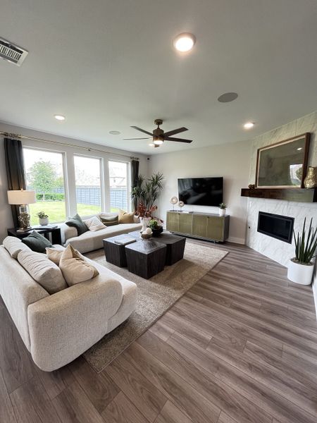 A spacious living room with modern sofas, a sleek fireplace, and wood flooring for a cozy and stylish atmosphere.