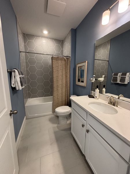 A sophisticated primary bathroom with dual sinks, gold fixtures, and a walk-in shower, blending elegance with functionality in Crossroads at Kelly Park by Dream Finders Homes (Apopka, FL).