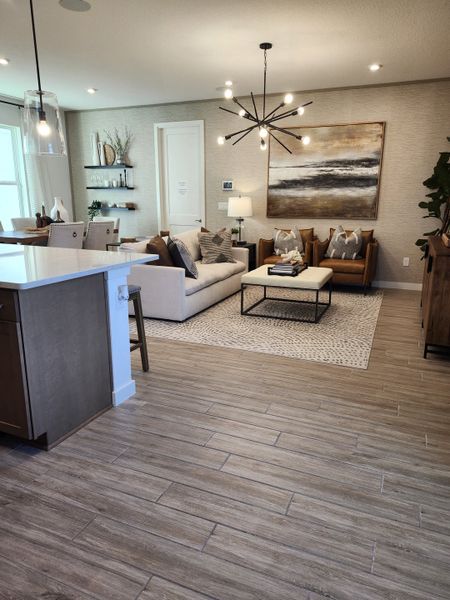 A cozy living area with modern fixtures, stylish decor, and elegant lighting on wood-like tile flooring.