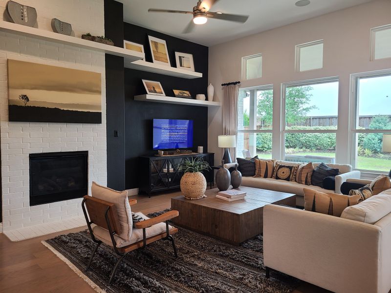 A modern living room with sleek shelving, neutral tones, a cozy fireplace, and large windows overlooking a lush backyard. A modern living room with sleek shelving, neutral tones, a cozy fireplace, and large windows overlooking a lush backyard.