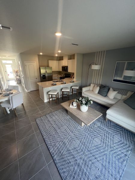 A chic living area with a modern kitchen, cozy sofa, and stylish decor, featuring a sleek design and soft lighting.