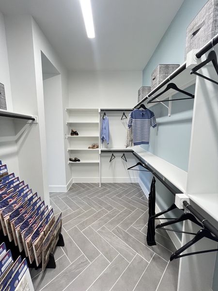 A spacious walk-in closet with elegant herringbone tile flooring and ample shelving for organized storage. A spacious walk-in closet with elegant herringbone tile flooring and ample shelving for organized storage.