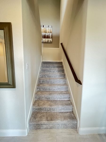 A modern staircase with plush carpeting and elegant wall art, leading to an upper level.