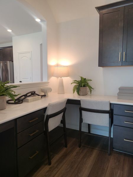 A modern workspace featuring dark cabinetry, elegant lighting, and vibrant greenery for a refreshing home office vibe. A modern workspace featuring dark cabinetry, elegant lighting, and vibrant greenery for a refreshing home office vibe.