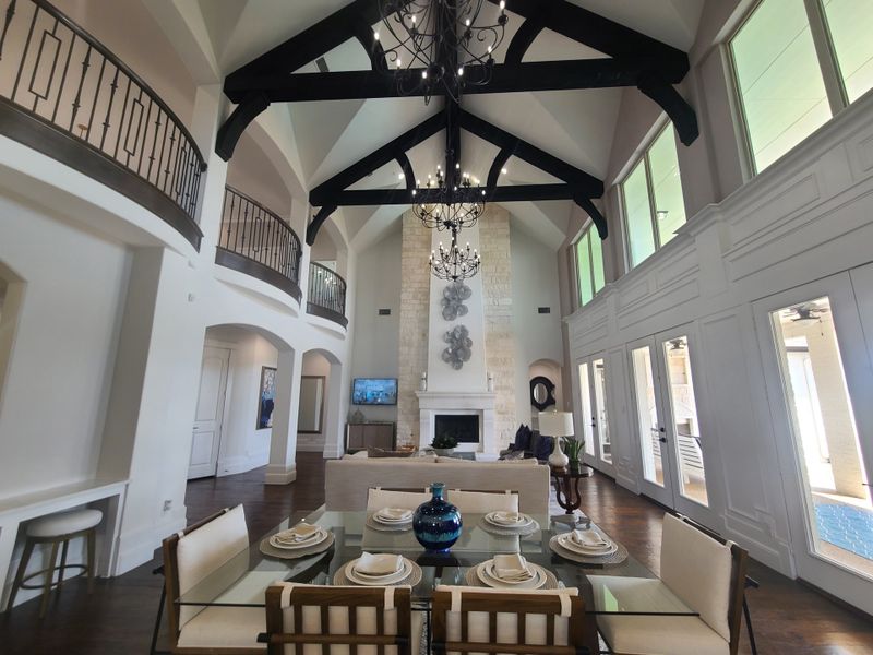 An elegant living room with vaulted ceilings, exposed beams, and a grand fireplace, featuring a stylish dining area. An elegant living room with vaulted ceilings, exposed beams, and a grand fireplace, featuring a stylish dining area.
