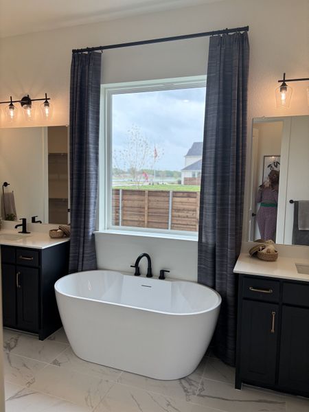 A modern bathroom with a sleek freestanding tub, dual vanities, and elegant lighting fixtures.