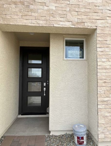 A modern entrance with a sleek black door and stone accents in Avalon Crossing Inspiration by Lennar (Mesa, AZ). A modern entrance with a sleek black door and stone accents in Avalon Crossing Inspiration by Lennar (Mesa, AZ).