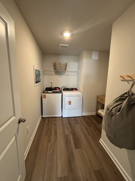 A cozy laundry room featuring a washer, dryer, and wooden flooring.
