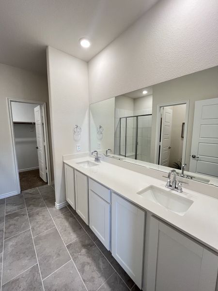 A sleek bathroom features a double vanity with white cabinetry, large mirror, and tiled flooring, creating a modern ambiance. A sleek bathroom features a double vanity with white cabinetry, large mirror, and tiled flooring, creating a modern ambiance.