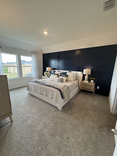 A spacious bedroom with a dark accent wall, cozy carpet, and large windows offering plenty of natural light. A spacious bedroom with a dark accent wall, cozy carpet, and large windows offering plenty of natural light.