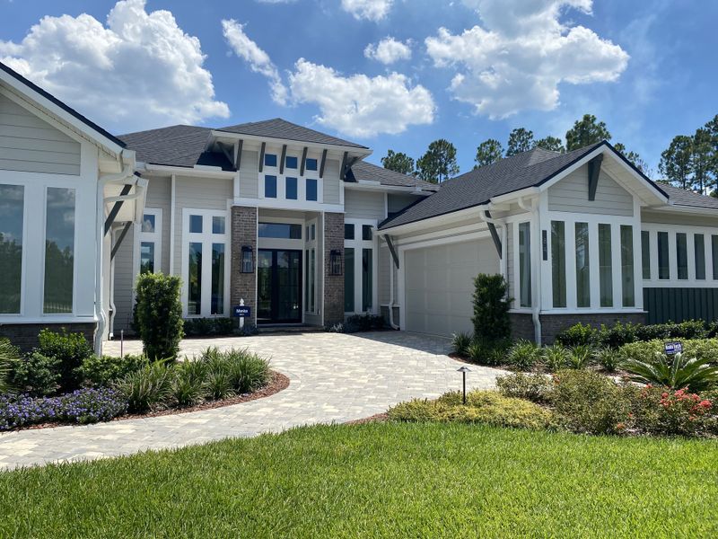 A modern home with expansive windows and lush landscaping in Courtney Grove at SilverLeaf by ICI Homes (St. Augustine, FL).