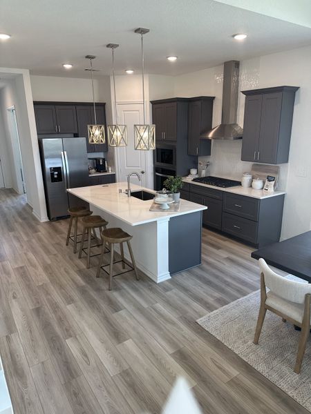 A modern kitchen featuring sleek dark cabinets, a large island with barstools, and elegant pendant lighting. A modern kitchen featuring sleek dark cabinets, a large island with barstools, and elegant pendant lighting.