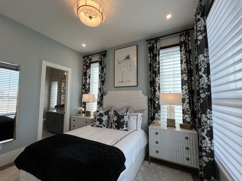 A cozy bedroom with floral drapes, elegant lighting, and a chic headboard, creating a tranquil and stylish retreat.