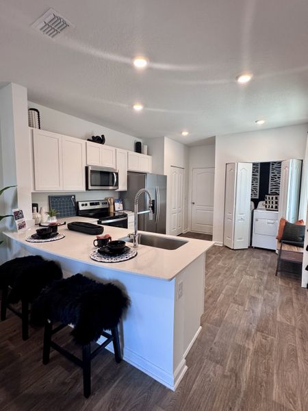 A modern kitchen with sleek white cabinetry, stainless steel appliances, and a stylish breakfast bar.