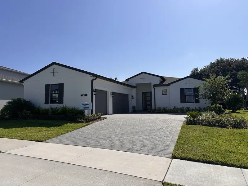 A modern white home with dark accents and manicured landscaping in Cresswind at Lake Harris by Kolter Homes (Tavares, FL).