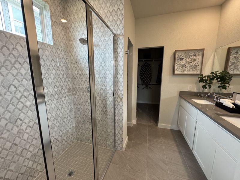 A modern bathroom with a glass shower, patterned tiles, sleek vanity, and elegant decor. A modern bathroom with a glass shower, patterned tiles, sleek vanity, and elegant decor.