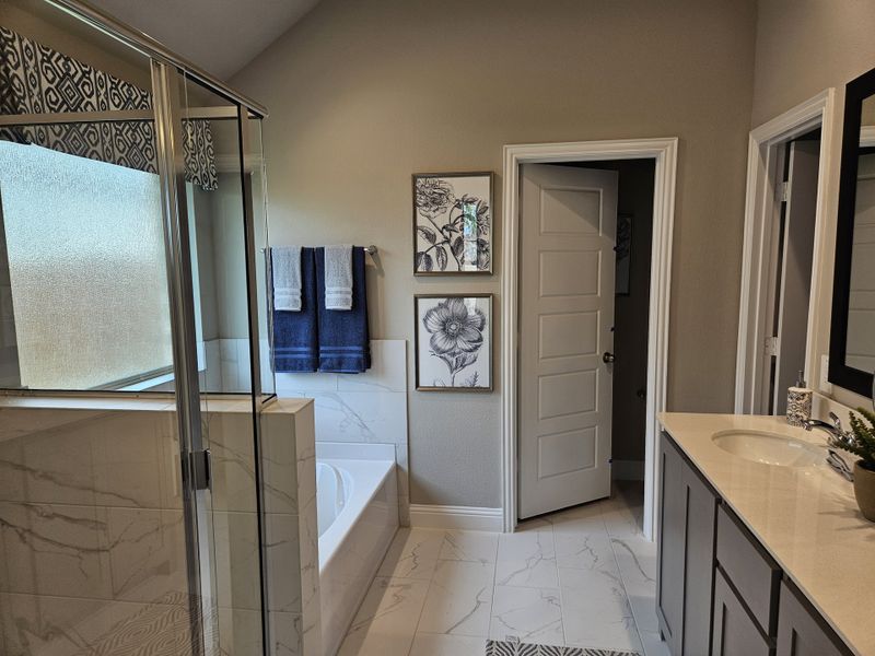 A modern bathroom featuring elegant marble flooring, a chic glass shower, and tasteful floral artwork. A modern bathroom featuring elegant marble flooring, a chic glass shower, and tasteful floral artwork.