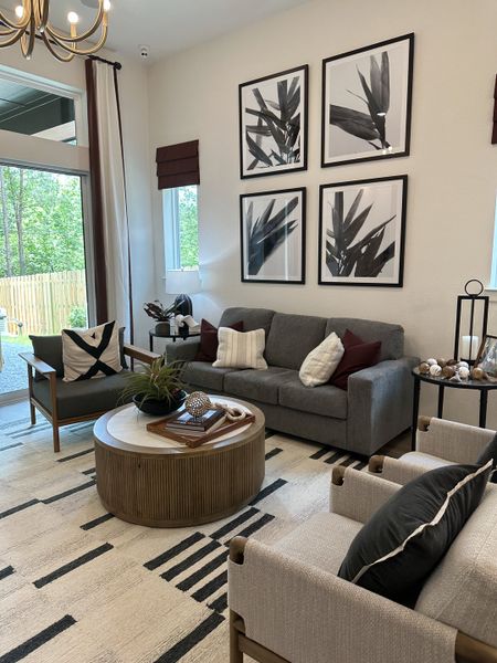 A modern living room with a gray sofa, abstract artwork, and wooden accents, filled with natural light.