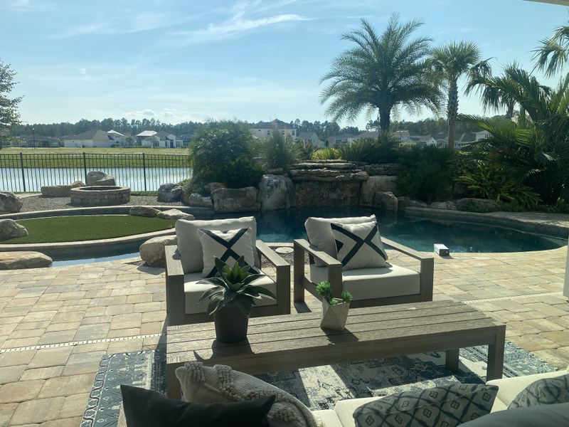 A serene backyard oasis with a lush pool view, cozy seating, and peaceful landscaping.