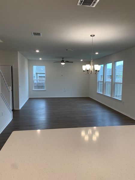 An open living space with wood floors, modern lighting, and large windows creating a bright, inviting atmosphere.